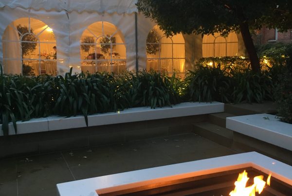 A large sheltered evening marquee used for a dining event, with an outdoor fire-pit