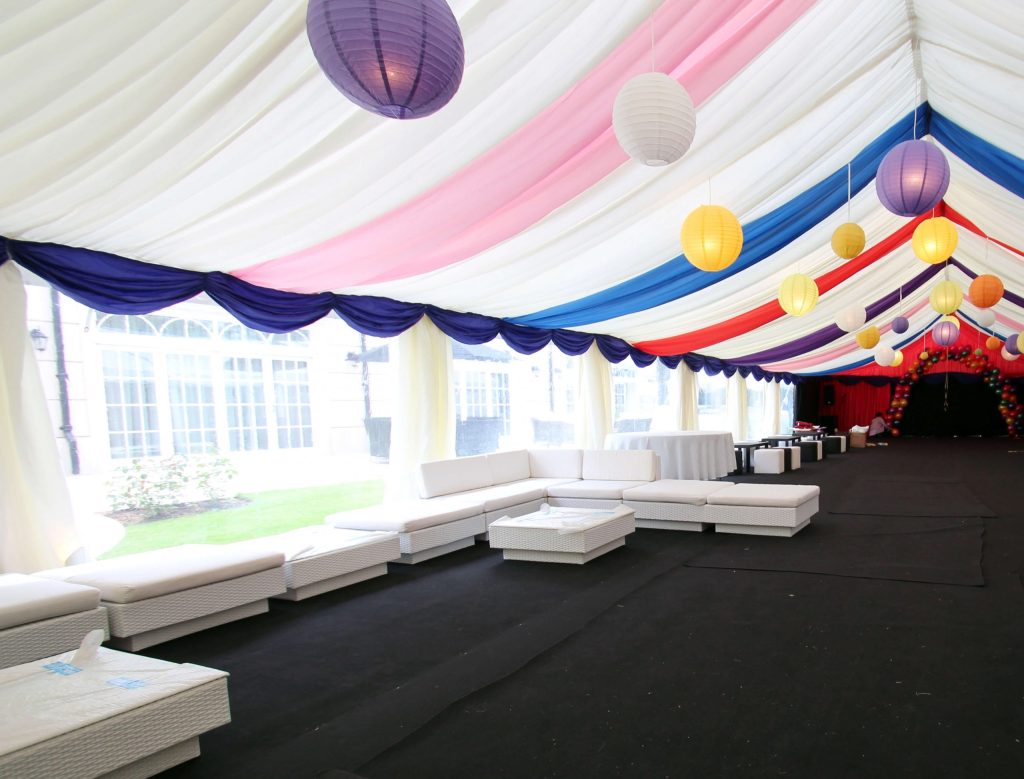 A multicoloured marquee with white sofas used for formal events and parties