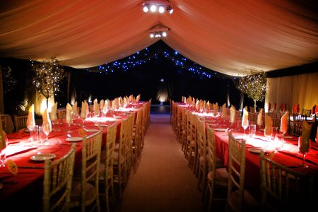 A evening event set up with fairy lights inside a marquee used to host a formal dinner.