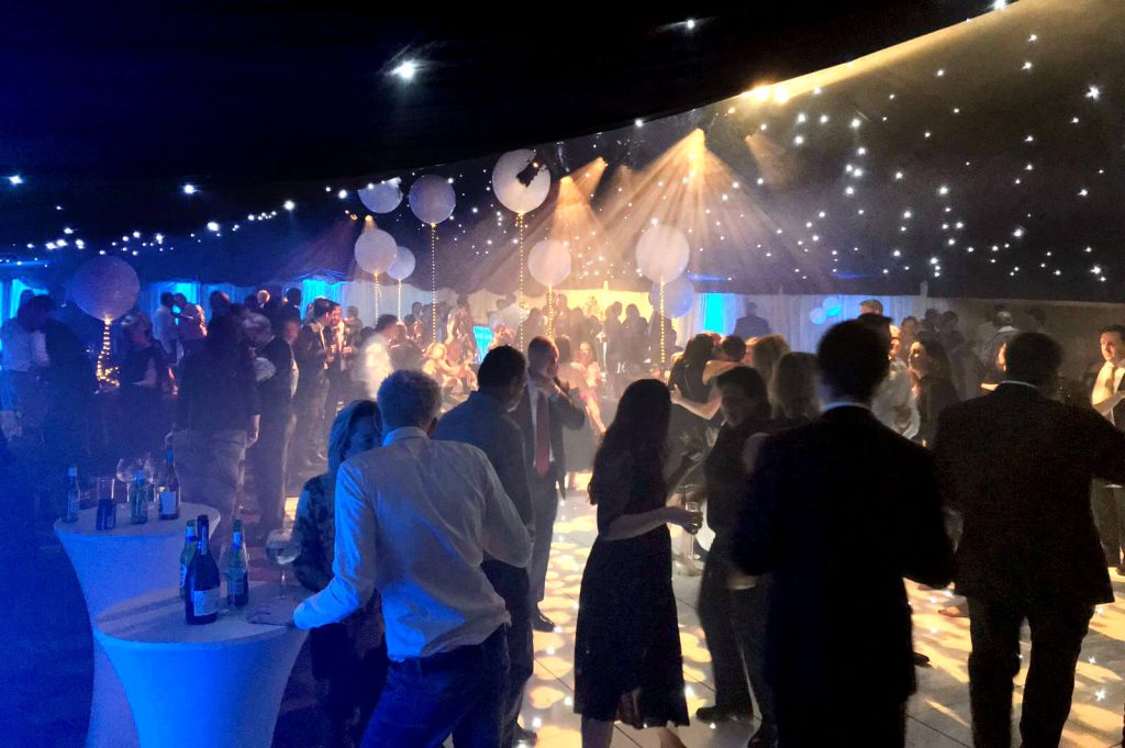 People enjoying a party inside a large, outdoor marquee