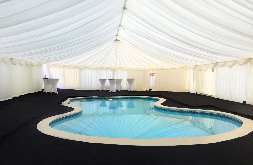Teper marquee built around a swimming pool with black carpet