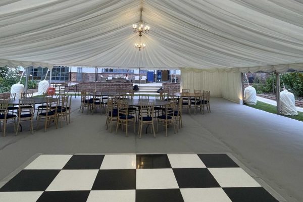 Internal view of marquee with black and white dance floor with ivory linings and silver carpet. Marquee hire London