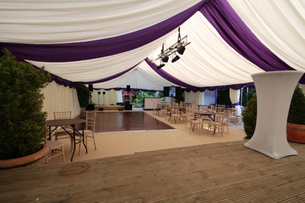 Marquee hire Surrey , an internal view with purple roof overlays and swag and champagne carpet